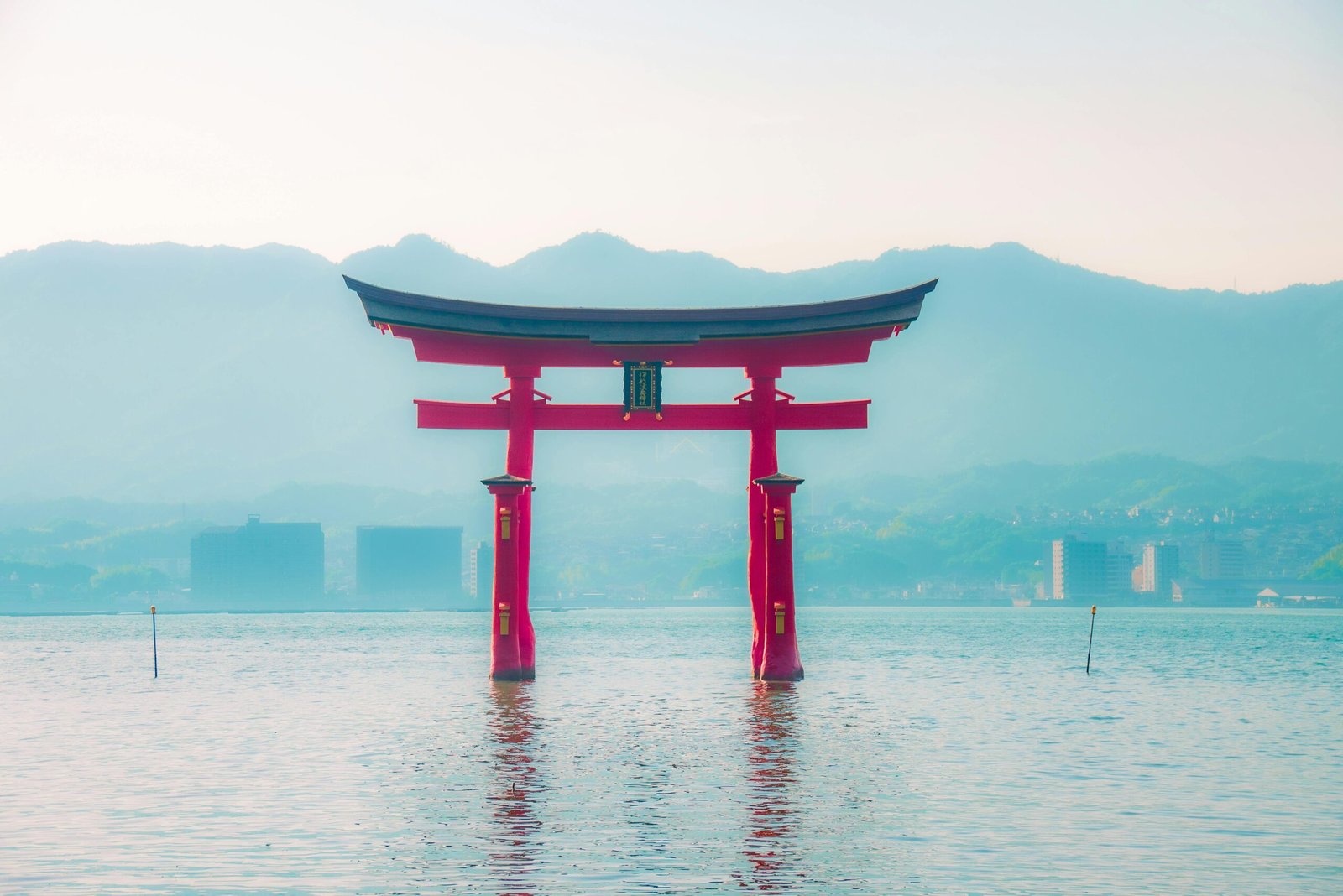 A captivating shot of the iconic Torii gate of Itsukushima Shrine, blending tradition with serene water and mountains.