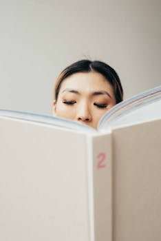 A young woman deeply engaged in reading a hardcover book, showcasing concentration and literacy.